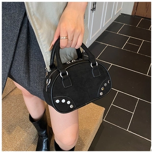 Détail du sac bowling en daim noir avec rivets argentés et accessoire bague en métal