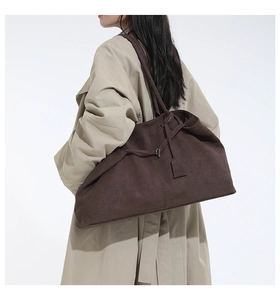 Détail du grand sac cabas en daim marron foncé montrant la sangle et la texture sur le modèle