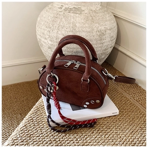 Vue détaillée du sac bowling en daim marron avec rivets et sangle tissée décorative