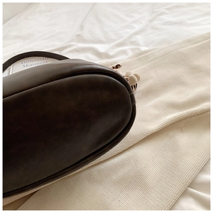 Detailed macro view of the oval base and fine stitching on the dark brown leather bucket bag