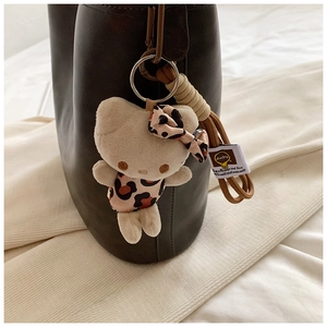 Detail of Hello Kitty plush charm with leopard print outfit on a black leather handbag