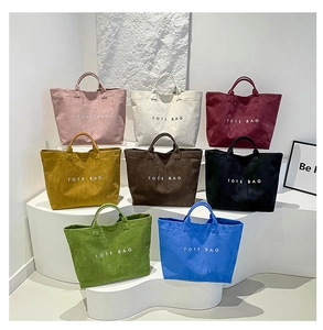Close-up of eight vibrant corduroy tote bags with white logo displayed on a podium