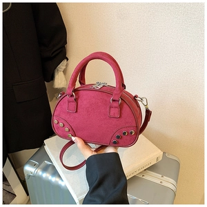 Gros plan du sac à main bordeaux en cuir dépoli avec rivets vintage et doubles poignées
