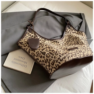 Detail of leopard print tote bag with brown trim and mini pouch on a stylish book