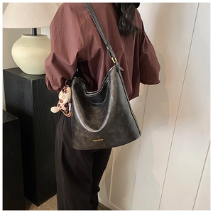 Detail of black vintage texture hobo bag with gold hardware and leopard cat charm