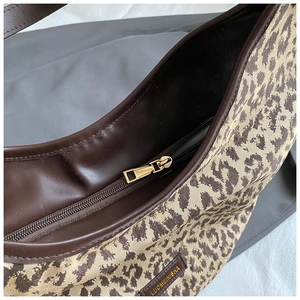 Detail of leopard print canvas tote featuring gold zipper and brown leather trim