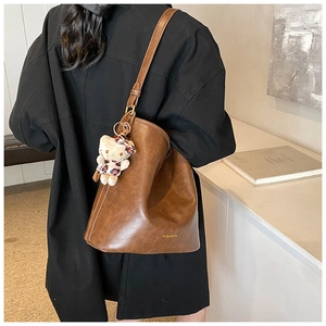 Detailed side view of deep brown vintage textured hobo bag with cute kitten charm pendant