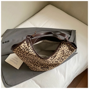 Detail of leopard print canvas tote featuring brown leather trim and metal logo plate