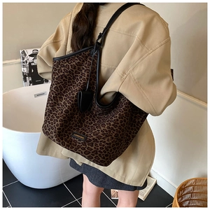 Detailed view of leopard print tote bag with black leather straps and brand logo