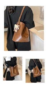 Detail view of brown vintage leather bucket bag with cute cat charm and golden logo