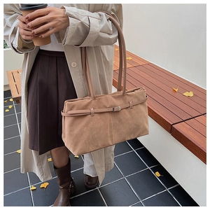 Gros plan du sac cabas en daim marron avec boucle métallique sur un fond style urbain