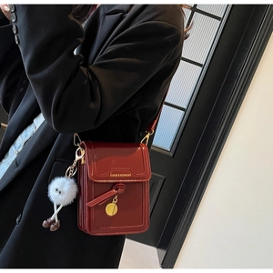 Detail of wine red crossbody bag with plush charm and fashion logo on model