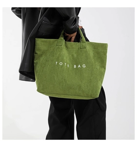 Macro view of green tote bag showing matte texture and white TOTE BAG printing