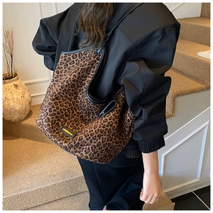 Detailed shot of large leopard print canvas tote bag with leather straps on a model