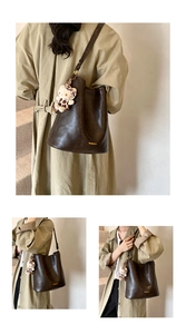 Detail of dark brown leather bucket bag featuring a gold logo and vintage texture