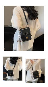 Three-way view of a sleek black square crossbody bag with a plush charm accessory