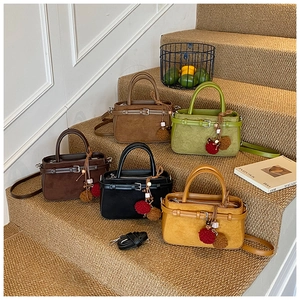 Five assorted matte leather handbags arranged on carpeted stairs with furry pom-poms