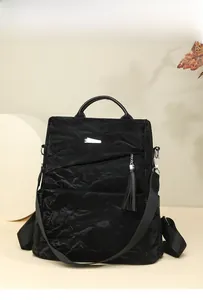 Detail of black backpack featuring a unique crinkle texture and a stylish tassel pendant