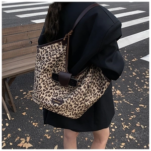 Leopard print canvas tote bag with leather strap and sunglass holder on street background