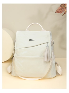 Detail of cream minimalist backpack featuring metallic hardware and elegant tassel charm