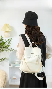 Rear view of a stylish off-white faux leather backpack with tassel on a female model