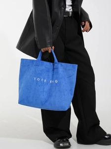 Klein blue large capacity tote bag with white lettering shown on a model