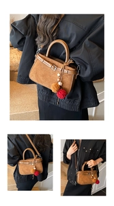 Detail of brown suede crossbody bag with decorative buckles and colorful pompom pendant