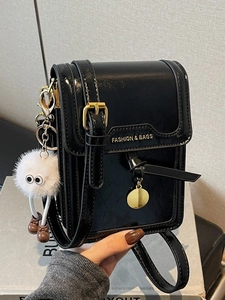 Glossy black crossbody bag with white plush charm and golden metal hardware