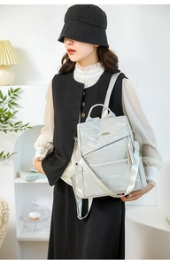 Detailed view of silver pleated backpack with tassel charm and multiple zip pockets