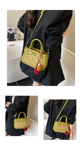 Detail of olive green handbag with suede texture, buckle strap and plush charm
