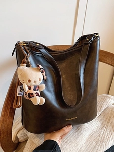 Deep brown vintage leather hobo bag with plush charm shown in a cozy home setting