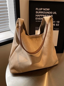 Minimalist beige matte tote bag with brown leather handles on a polished metal surface