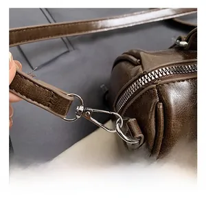 Close-up of silver metal hooks and premium dark brown oily leather on Boston bag