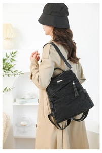 Detail of black backpack showing crinkled texture fabric and silver metallic accents