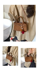 Detailed view of dark brown suede handbag with plush ball pendant and versatile straps