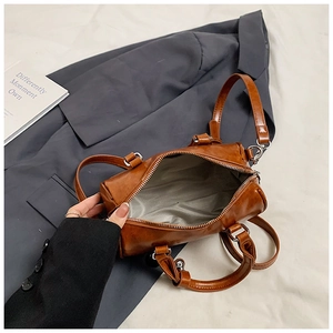 Detail view of brown Boston bag interior with gray lining and smooth metal zipper