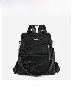 Detailed front view of black textured rucksack with fringe charm and silver hardware