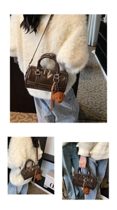 Close-up of brown PU leather boston bag with retro hardware and bear plush pendant