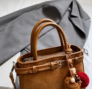 Detail of vintage brown leather bag featuring suede splicing and decorative charms