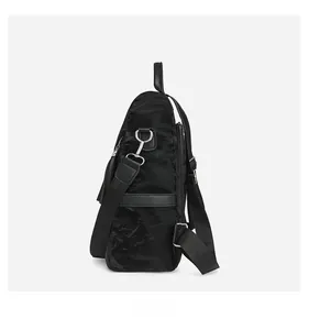 Side view of black nylon backpack showing textured fabric, leather trim, and silver hooks
