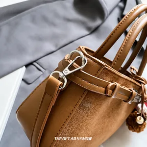 Close-up of premium brown leather stitching and silver metal spring hook details
