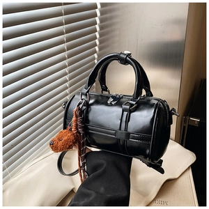 Detail of a black Boston bag with glossy finish and cute brown teddy bear charm
