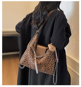 Detail of leopard print hobo bag with brown leather strap and cute plush bear charm