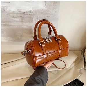 Close-up of brown Boston bag showing textured faux leather and polished silver hardware