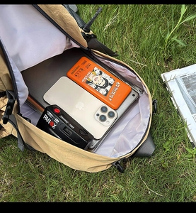 Macro view of outdoor backpack interior organized with laptop, camera and gadgets on grass