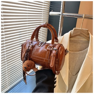 Close-up of retro brown Boston bag with dual handles, metal zippers and plush dog charm