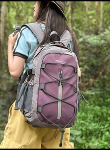 Detail of outdoor backpack with purple and grey panels, elastic cord system and side mesh pockets