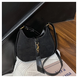 Detail of black crescent bag showing contrast between suede texture and glossy patent leather