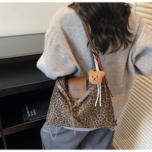 Detail of leopard print tote bag featuring brown leather flap and cute bear pendant