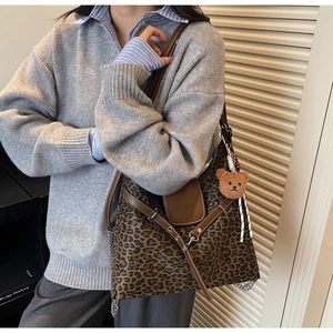 Close-up of leopard print shoulder bag with chain strap and cute bear charm accessory